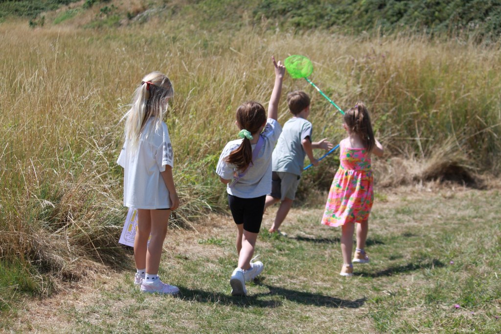 Photo of children running in field with insect nets